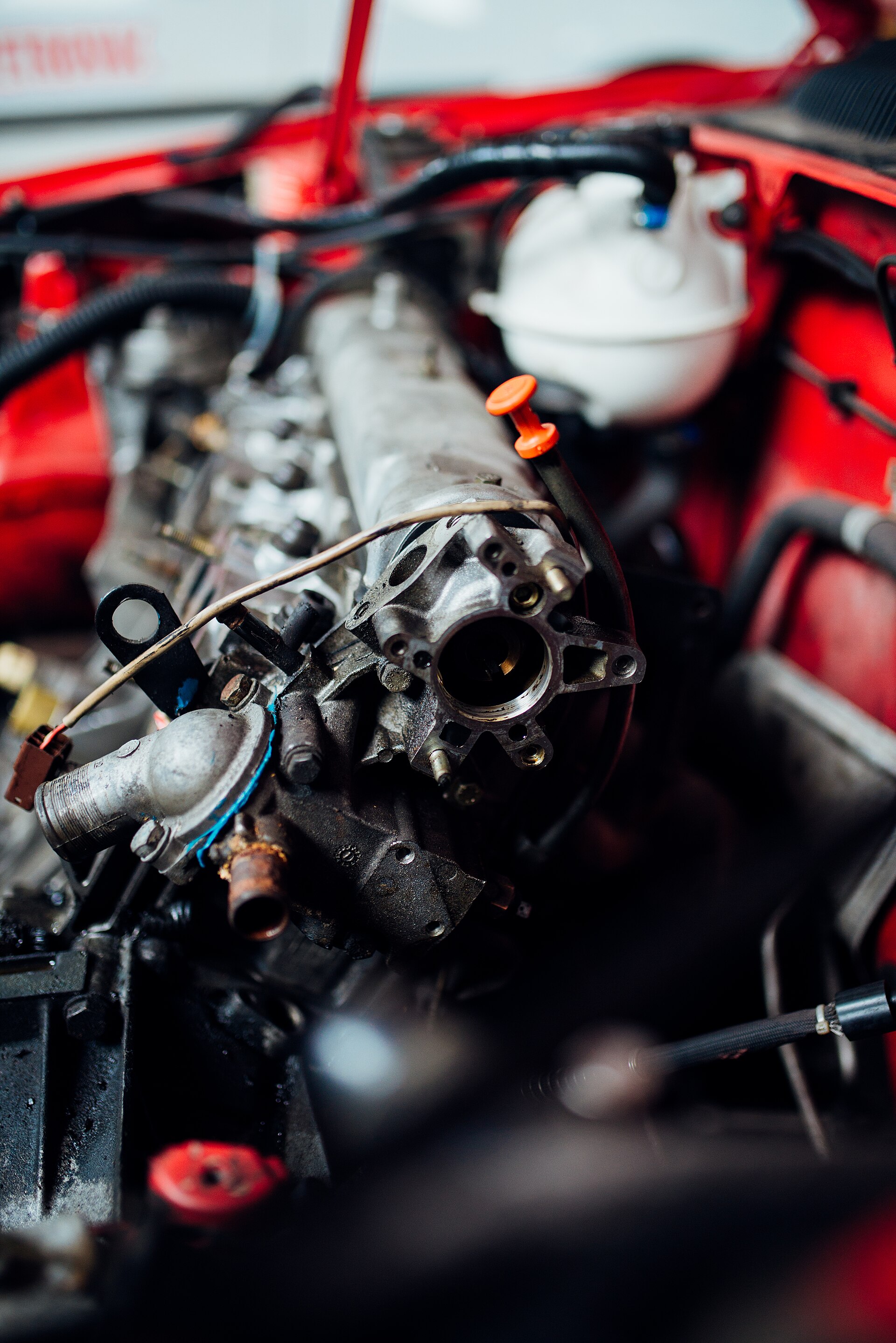 Collecteur d'admission déposé au-dessus d'un moteur, carrosserie rouge visible autour du compartiment