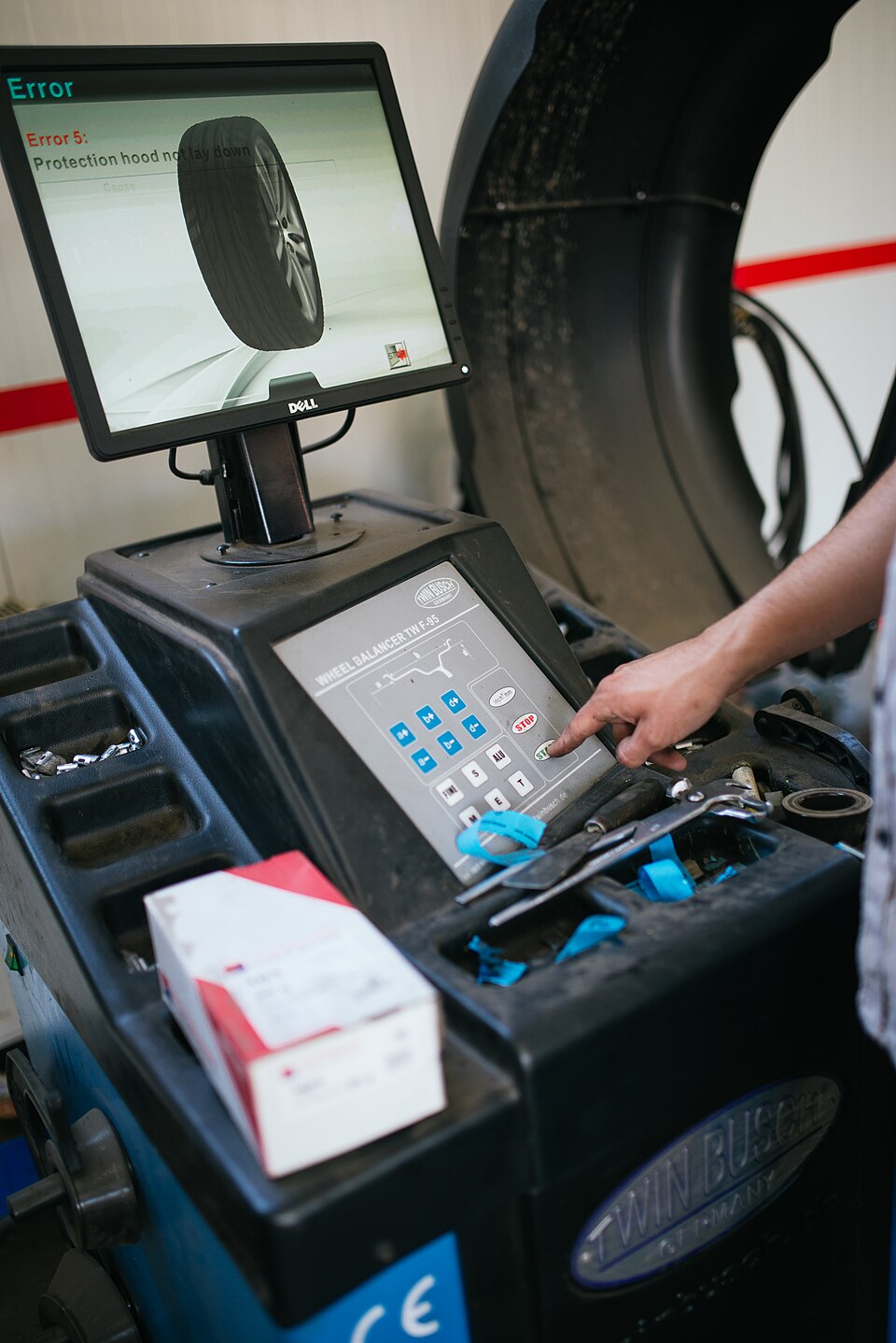 Technicien réglant un banc de géométrie devant une roue montée sur la machine
